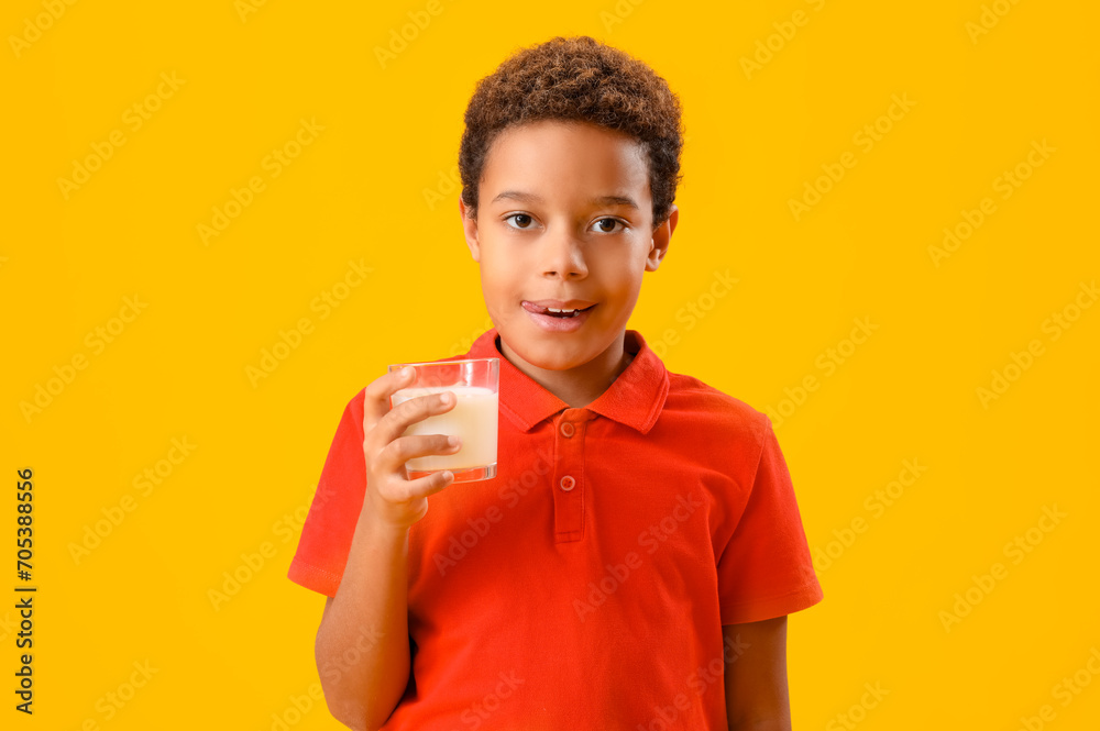 Little African-American boy with glass of milk on yellow background Little African-American boy with glass of milk on yellow background