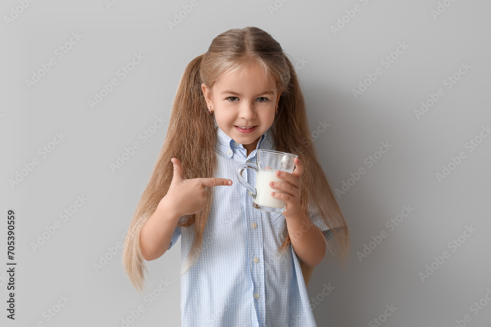 Cute little girl pointing at glass of tasty milk on grey background Cute little girl pointing at glass of tasty milk on grey background