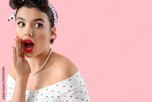 Shocked young pin-up woman gossiping on pink background, closeup photo