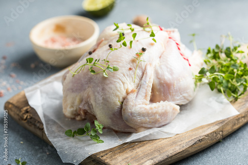 organic raw whole chicken with thyme peppers and garlic on a rustic table photo