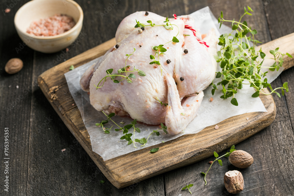 organic raw whole chicken with thyme peppers and garlic on a rustic table organic raw whole chicken with thyme peppers and garlic on a rustic table