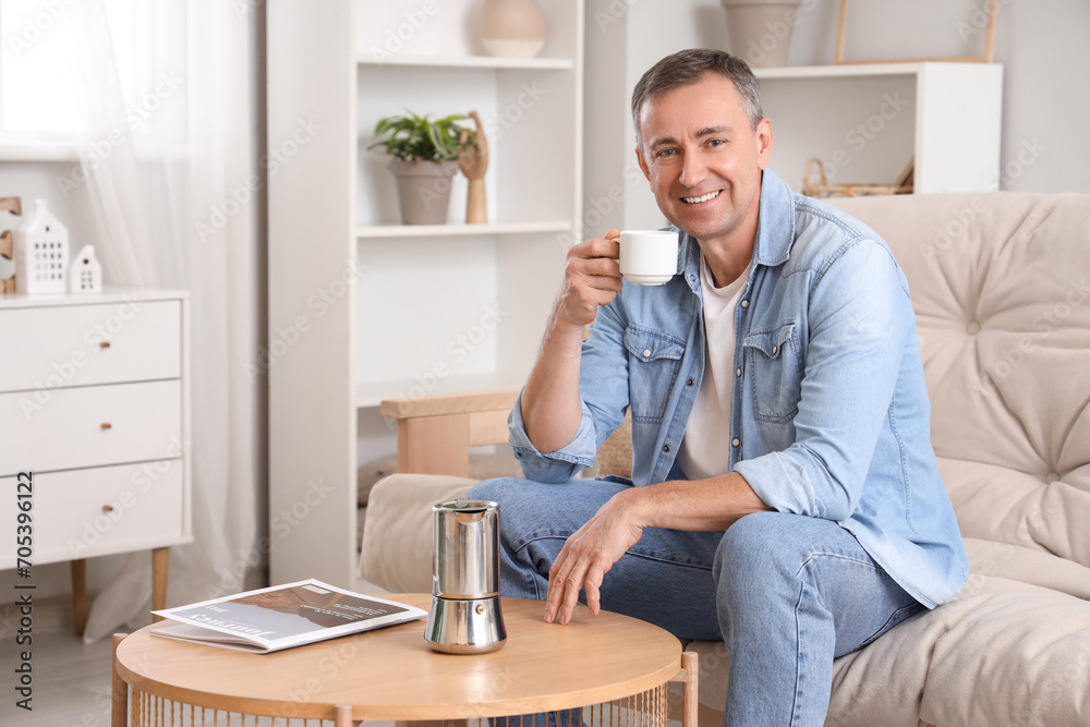 Mature man with cup and geyser coffee maker on table at home