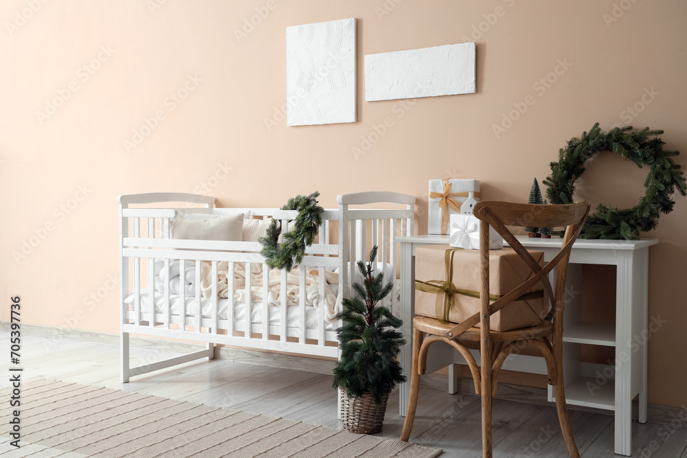 Interior of bedroom with baby crib, Christmas tree and table