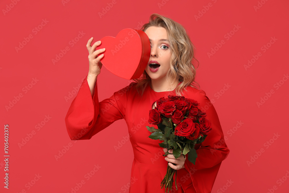 Shocked young woman with bouquet of beautiful roses and gift box on red background Shocked young woman with bouquet of beautiful roses and gift box on red background