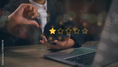 Businesswomen chose a 1-star rating review in the survey on the virtual touch screen on smartphones. Bad review, bad service dislike bad quality, low rating, social media not good photo