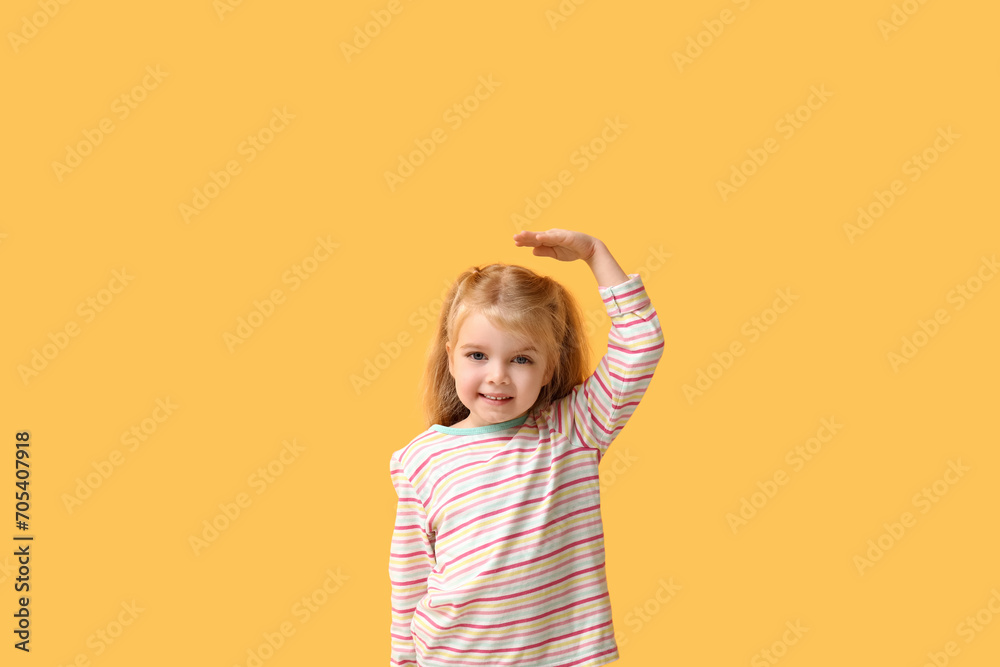 Cute little girl measuring height on yellow background Cute little girl measuring height on yellow background