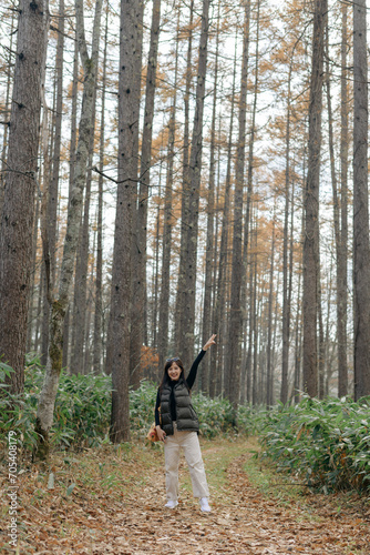 Asian woman hiking in Japan, enjoying nature's fall beauty on a scenic trail with a backpack