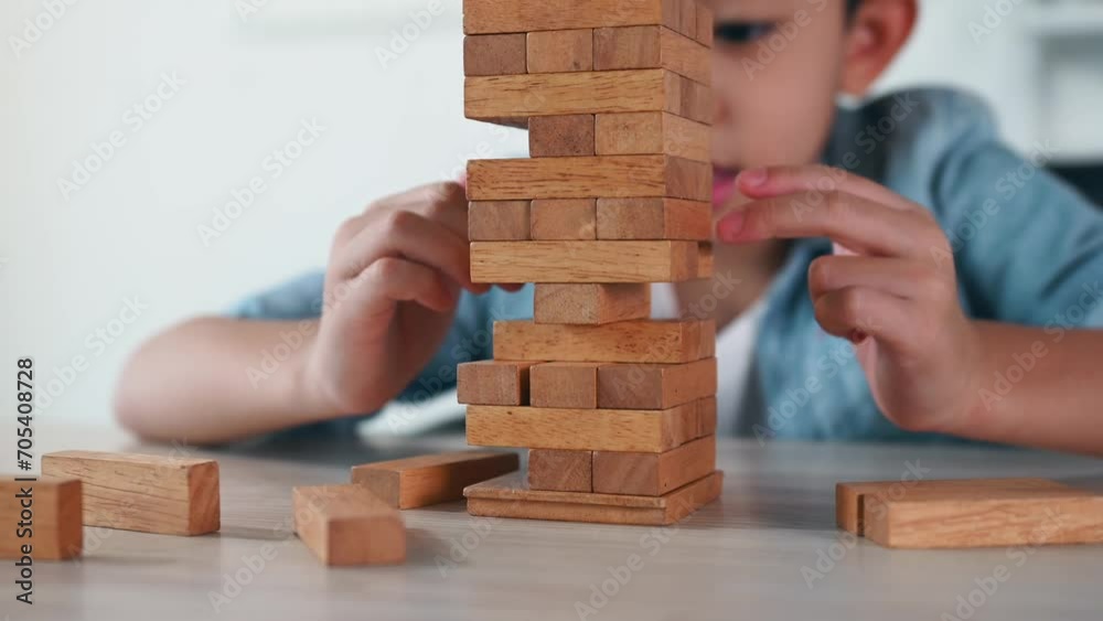 Child Boy Playing Jenga Game Exciting on Desk at Home. Unleashing Fun and Skill. Careful and Attentive Keeping, Concentrate and Slowly Take It Out while Playing. Study and learn to balance objects. Child Boy Playing Jenga Game Exciting on Desk at Home. Unleashing Fun and Skill. Careful and Attentive Keeping, Concentrate and Slowly Take It Out while Playing. Study and learn to balance objects.
