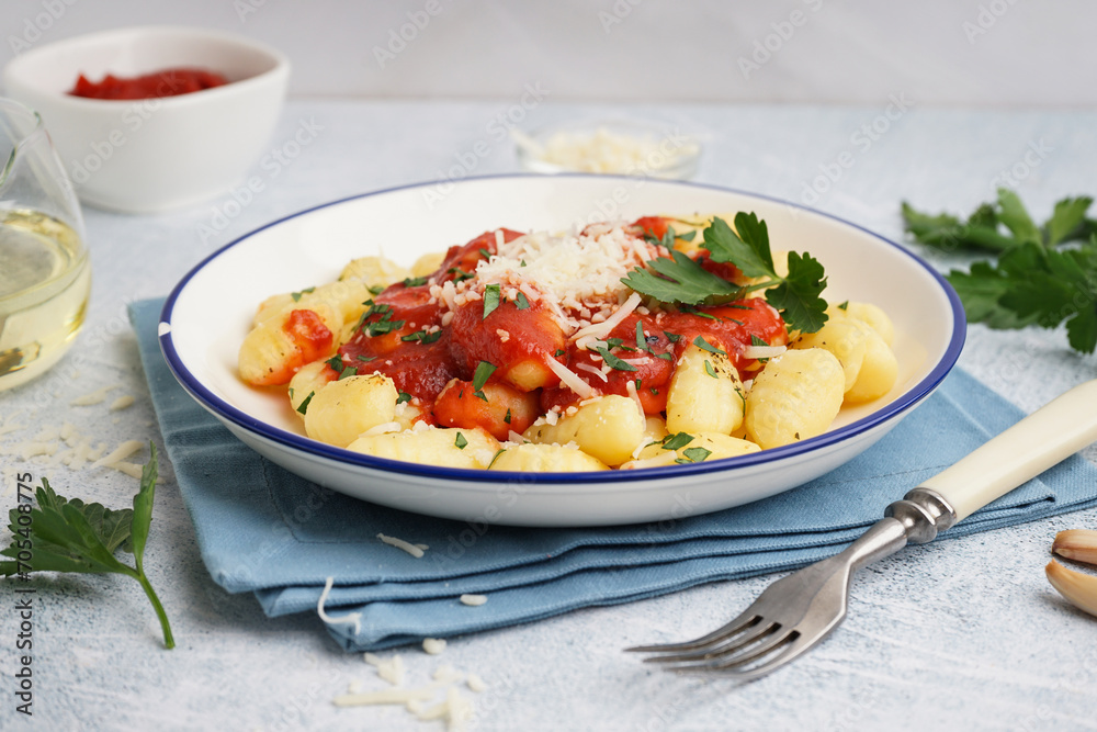Plate of tasty gnocchi with tomato sauce and cheese on blue background Plate of tasty gnocchi with tomato sauce and cheese on blue background