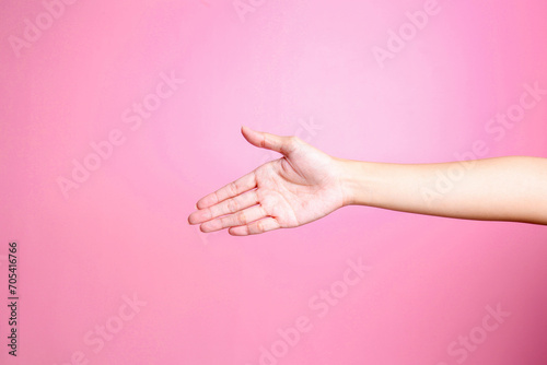 Hand offering hand shake isolated over pink background. Greeting concept  hand gesture