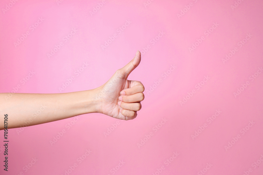 Side view of hand showing thumbs up over pink background