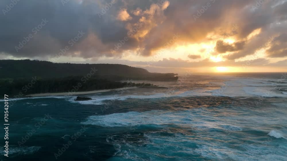 Aerial drone video captures the enchanting golden hour sunset in Hawaii, with big waves in the ocean. Aerial drone video captures the enchanting golden hour sunset in Hawaii, with big waves in the ocean.