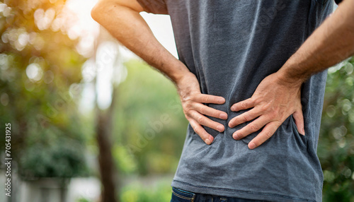 Man in discomfort, holds lower back, signifying back pain and healthcare concern