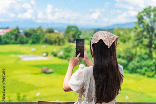 Young happy woman tourist enjoying and relaxing with beautiful landscape view rice paddy field while traveling at Nan, Thailand