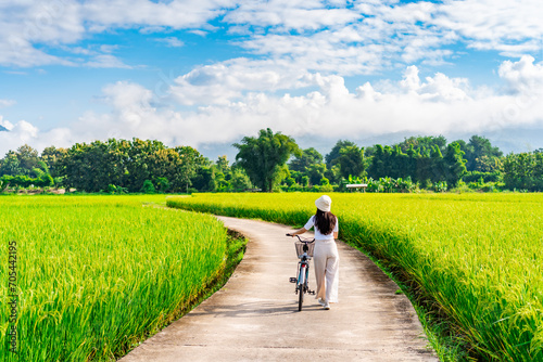 Young happy woman tourist enjoying and riding a bicycle in paddy field while traveling at Nan, Thailand photo