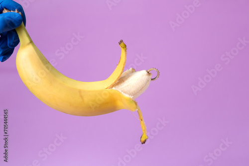 Intimate piercing. Minimal piercing concept. Banana with inserted iron decoration, piercing