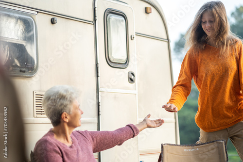Multi-generation family sitting and eating outdoors by car, caravan holiday trip, Family vacation parents enjoy bonding camping in woods travel