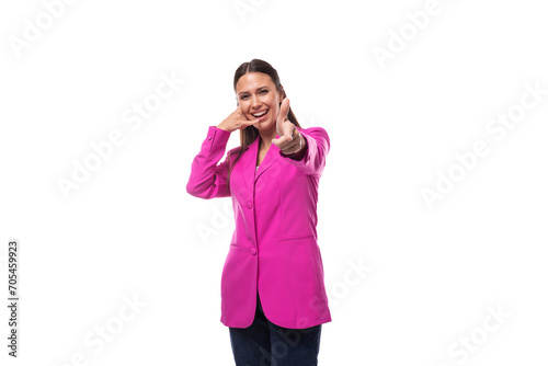 young smiling slender caucasian brunette boss woman in a pink jacket greets