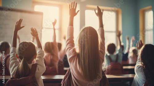 schoolgirls raised hand in classroom with teacher  photo