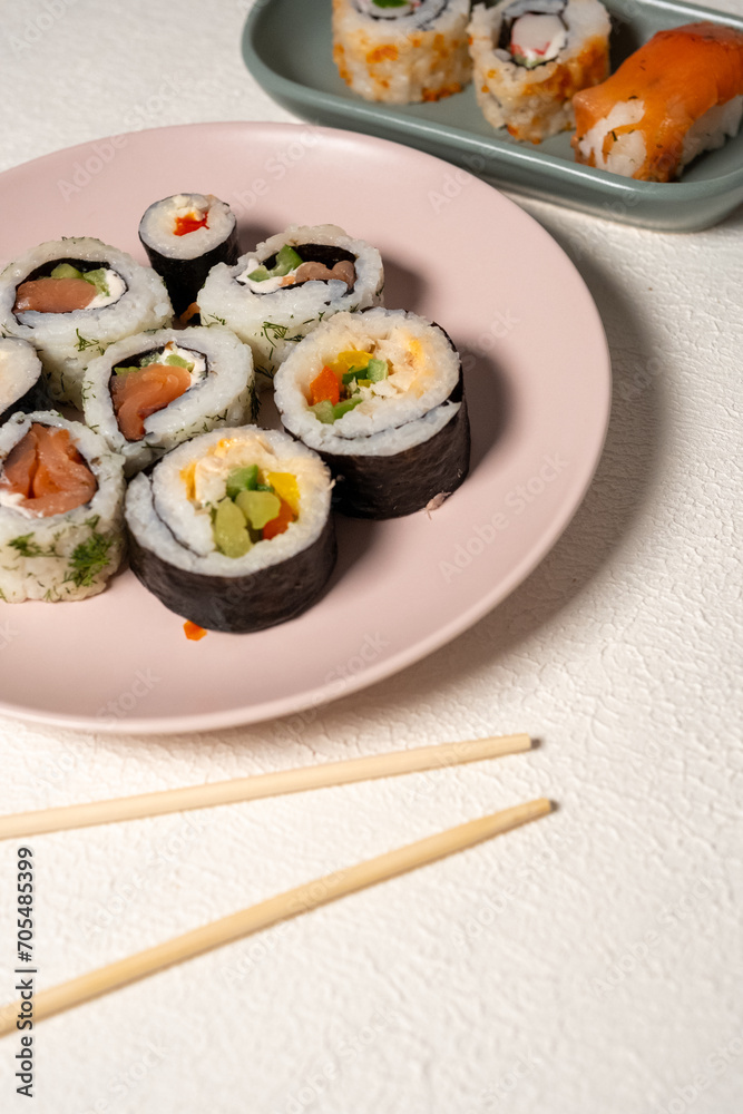Chop sticks, mushrooms, noodle ramen, California rolls and Philadelphia rolls on a small plate on a pink background
Chop sticks, mushrooms, noodle ramen, California rolls and Philadelphia rolls on a small plate on a pink background