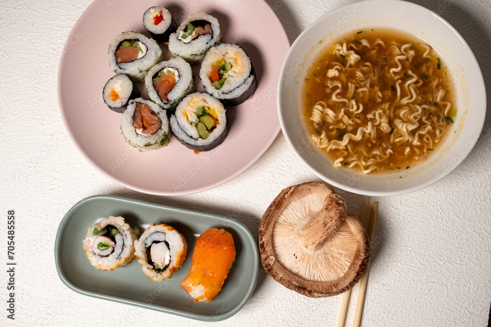 Chop sticks, mushrooms, noodle ramen, California rolls and Philadelphia rolls on a small plate on a pink background
Chop sticks, mushrooms, noodle ramen, California rolls and Philadelphia rolls on a small plate on a pink background