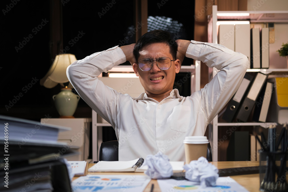 Young businessman working overtime on a desk at night.. Young businessman working overtime on a desk at night..