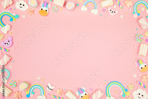 Cute pastel pink kawaii background with frame made of cute air plasticine handmade cartoon animals, unicorns, stars, rainbows. Flat lay, top view, copy space. Beautiful childlike design template