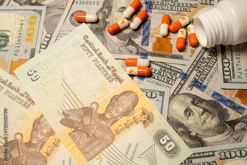 Egyptian money on american dollar and medicines in pill form in close-up 