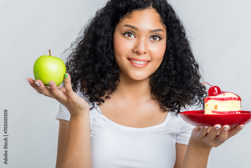 composition of choice. a girl stands on a light background and holds in her hands a green apple and a beautiful red cake composition of choice. a girl stands on a light background and holds in her hands a green apple and a beautiful red cake