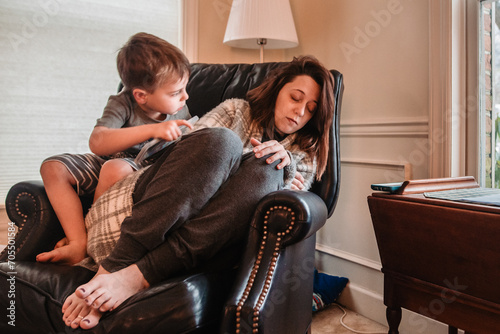 Child climbs on chair to look at sleeping mother photo