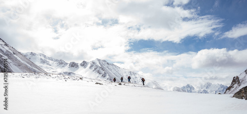 A group of people walking on the snowy mountains with their snowshoes on. Climbing the icy mountains