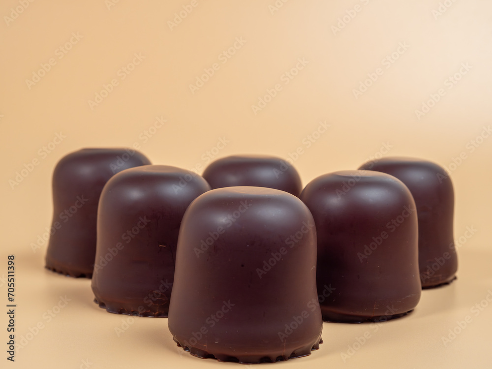 Naklejka premium Marshmallows in chocolate glaze on an orange background. Marshmallow close-up.