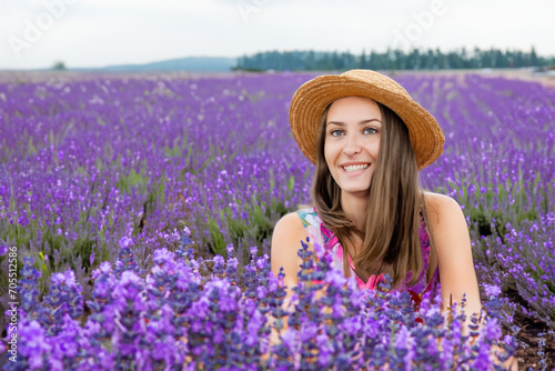 girl on the field. cheerful girl in a straw hat sits on a large field of purple lavender, nature concept