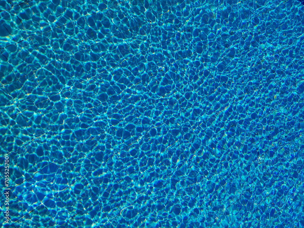 Blue water ripple in swimming pool with sun reflections