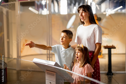 Foto Mom with kids are excited to interact with a robot, visiting together science museum