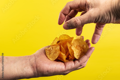 Potato chips in hand on yellow background