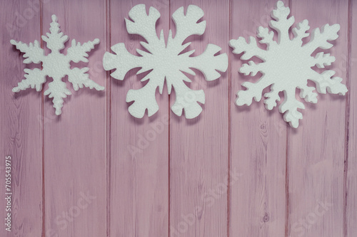 Three white snowflakes on a pink wooden background topview. New Years flatlay with copyspace