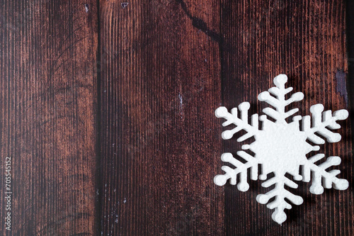 One snowflake on a brown wooden background. Christmas winter flatlay with copyspace 