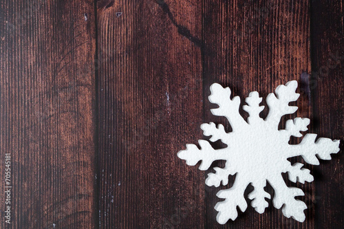 One snowflake on a brown wooden background. Christmas winter flatlay with copyspace 