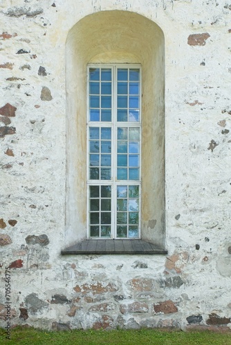 Wooden framed window with arch on a old stone building.