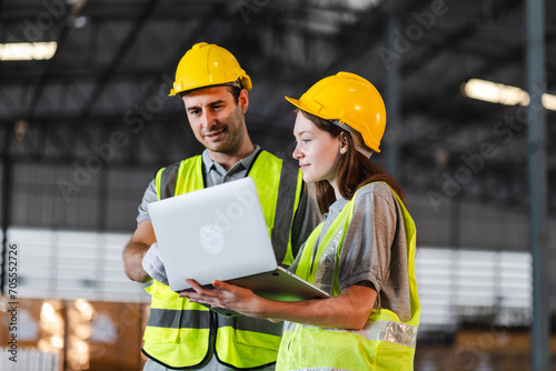 Engineer wearing safety vest controlling industrial machine working, talking with assistant worker checking first for labour with laptop computer, Officer setting a technology system in factory.