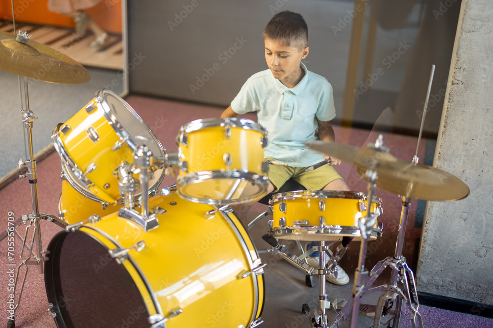 Fototapeta premium Little boy playing on a real drums, having fun while visiting a science museum