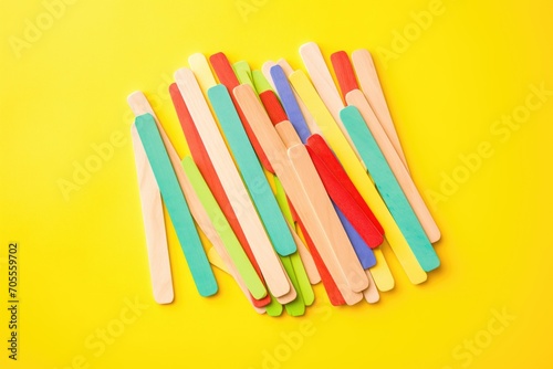 pile of colorful popsicle sticks on yellow background