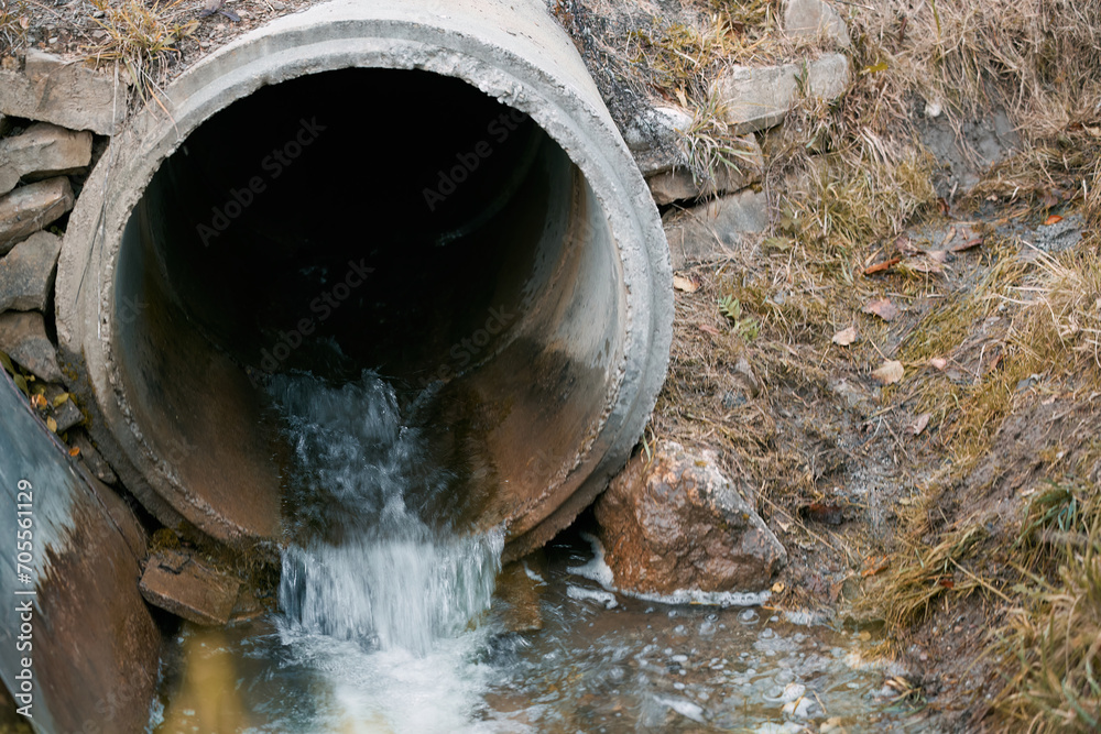 The river is polluted by industrial waste from a drainpipe that dumps sewage into the water, harming the natural ecosystem. The river is polluted by industrial waste from a drainpipe that dumps sewage into the water, harming the natural ecosystem.