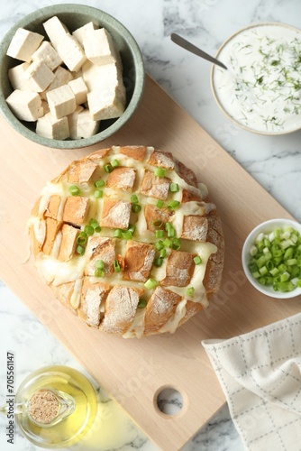 Freshly baked bread with tofu cheese and green onion served on white marble table, flat lay