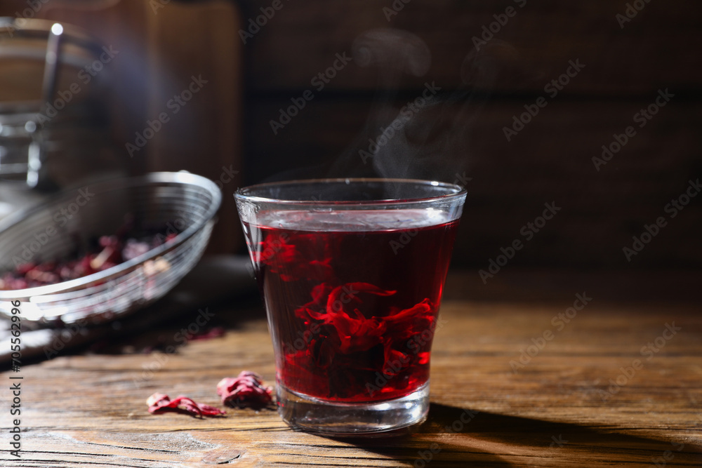 Delicious hibiscus tea in glass on wooden table, closeup Delicious hibiscus tea in glass on wooden table, closeup