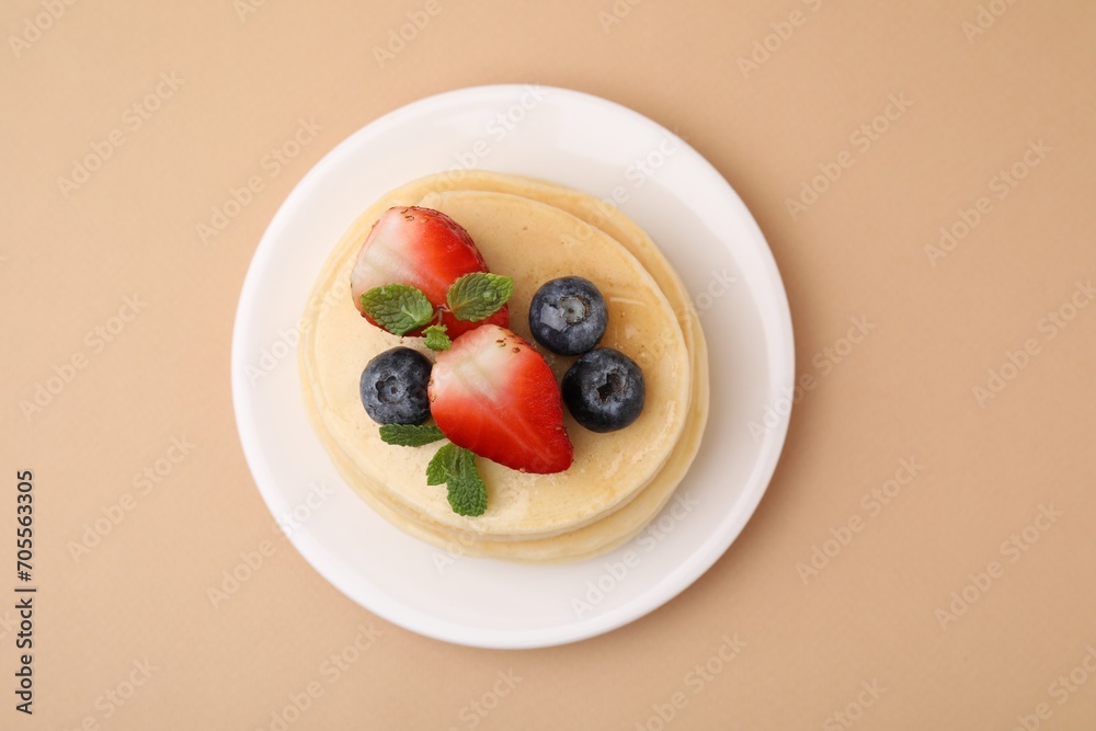 Stack of tasty pancakes with fresh berries and mint on beige background, top view Stack of tasty pancakes with fresh berries and mint on beige background, top view