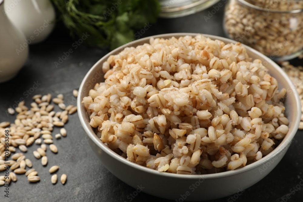 Tasty pearl barley porridge in bowl on dark table, closeup Tasty pearl barley porridge in bowl on dark table, closeup