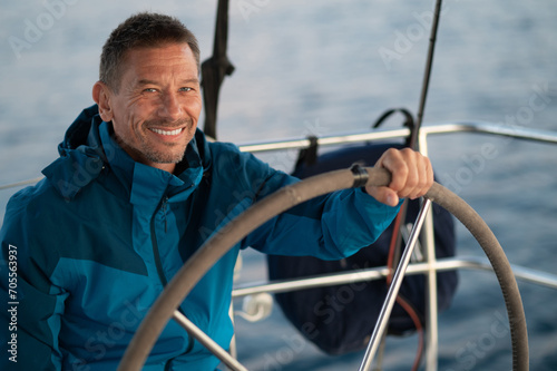 Good-looking mature man sailing a yacht and looking confident