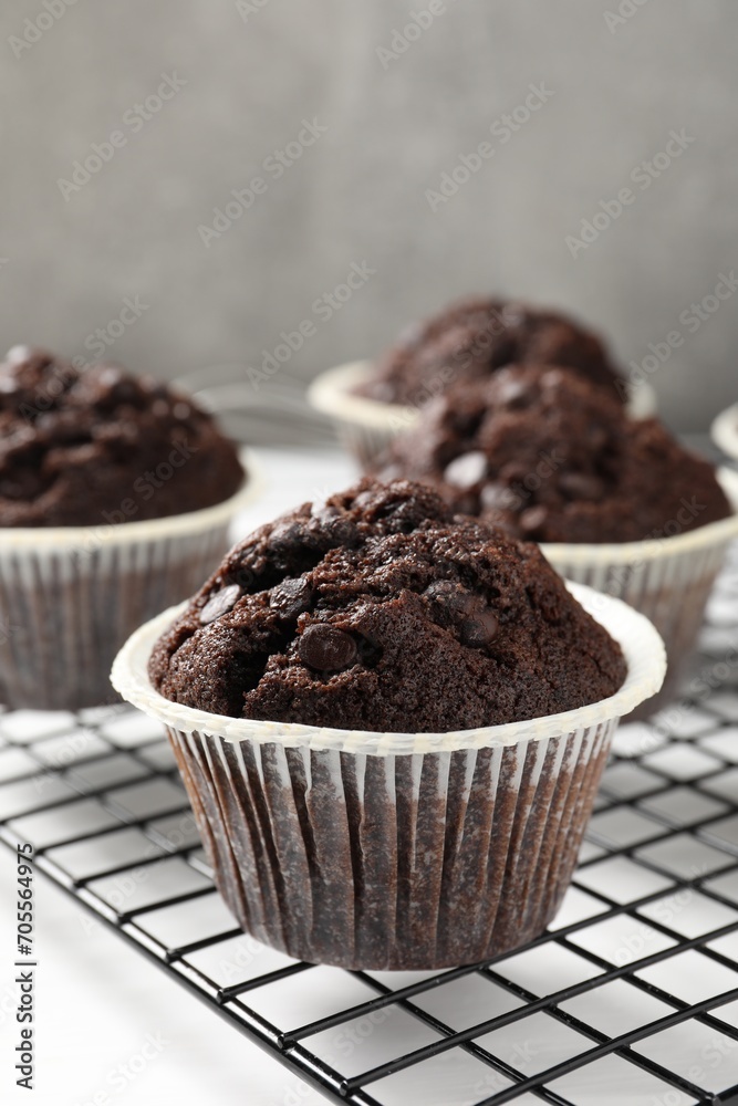 Tasty chocolate muffins and cooling rack on white table, closeup Tasty chocolate muffins and cooling rack on white table, closeup